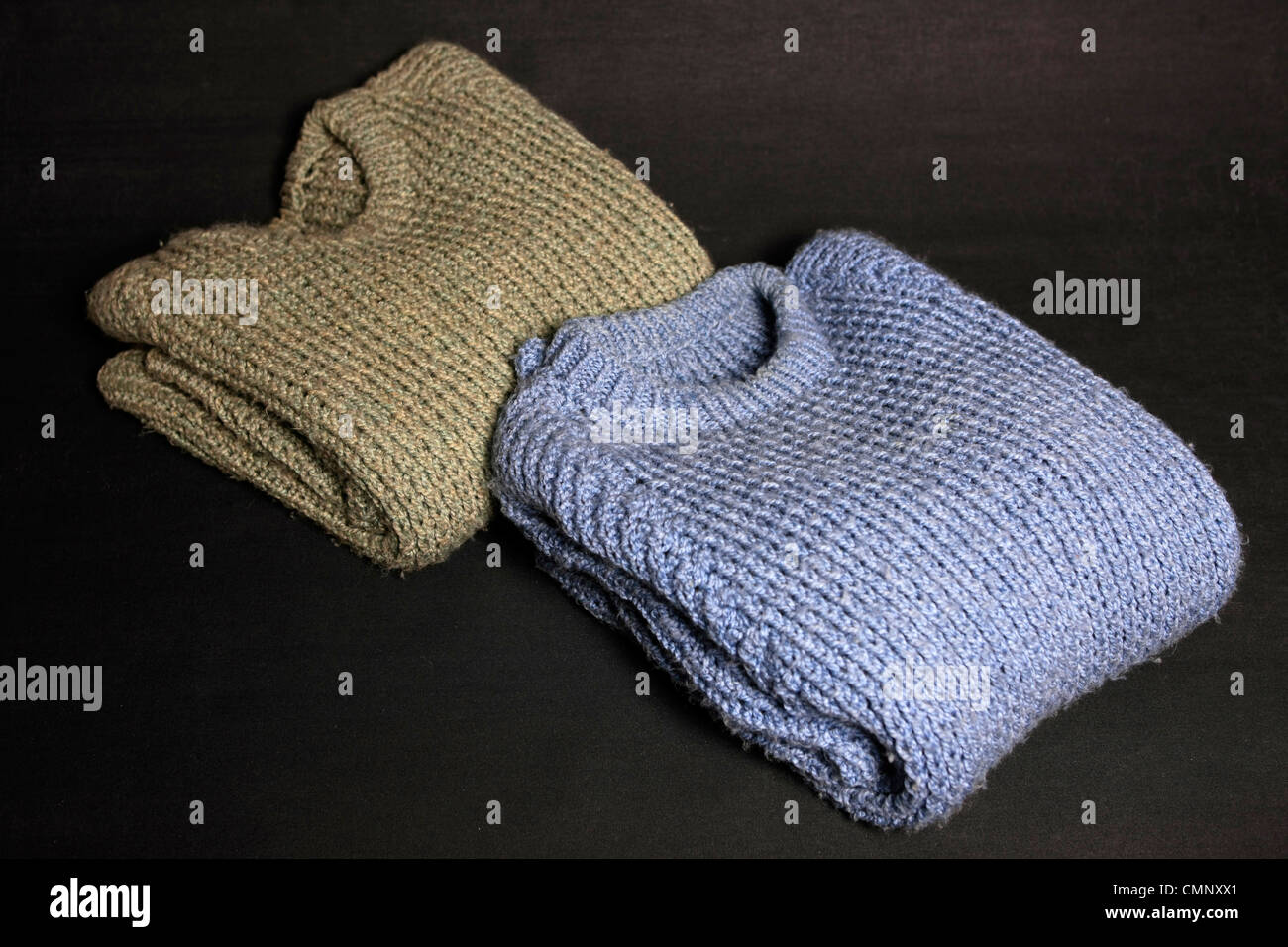 Un verde y azul plegada chunky knit Fisherman's sweater sobre un fondo negro Foto de stock