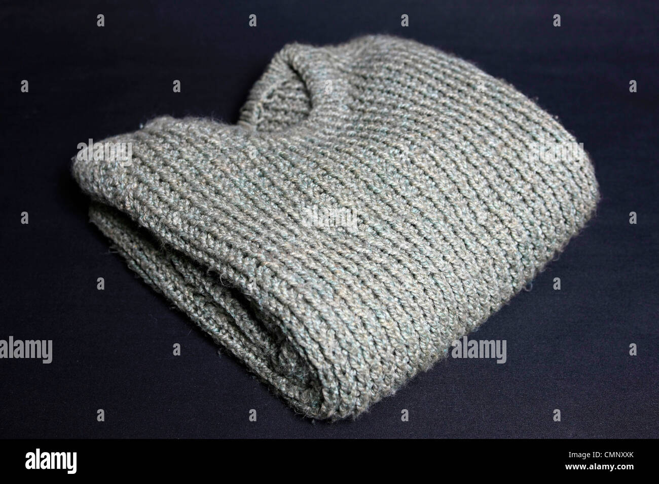 Un verde plegada chunky knit Fisherman's sweater sobre un fondo negro Foto de stock