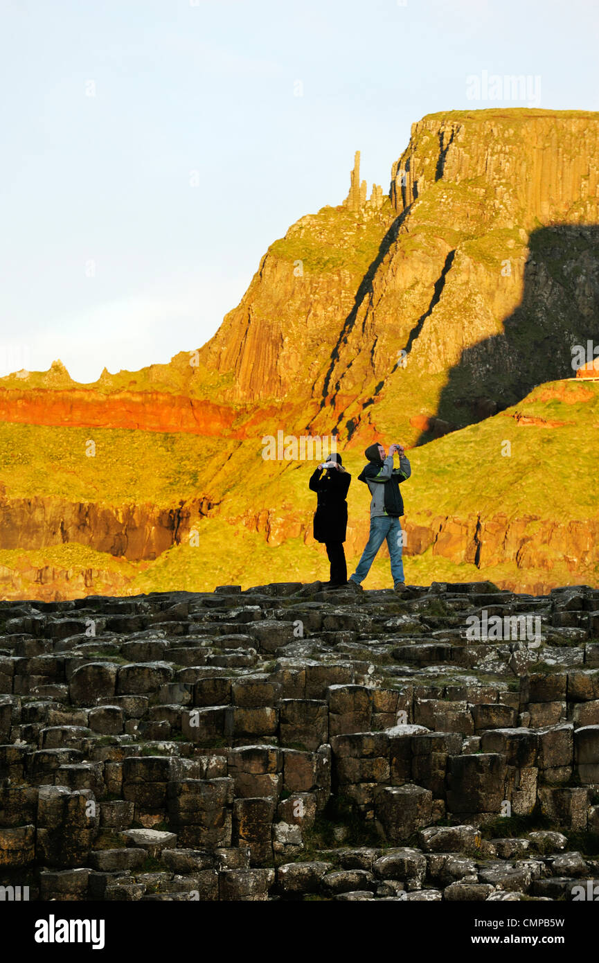 Los Giants Causeway, en Irlanda del Norte. Pareja de turistas toman fotografías en formaciones de roca basáltica conocida como la Grand Causeway Foto de stock