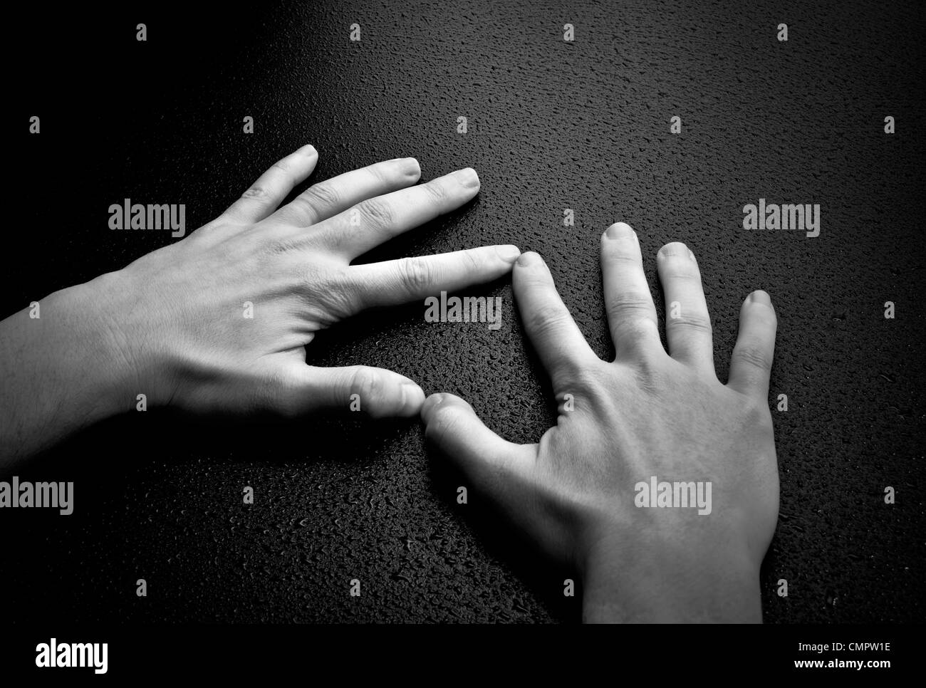 Dos manos creando una forma de corazón en la madera húmeda antecedentes Foto de stock