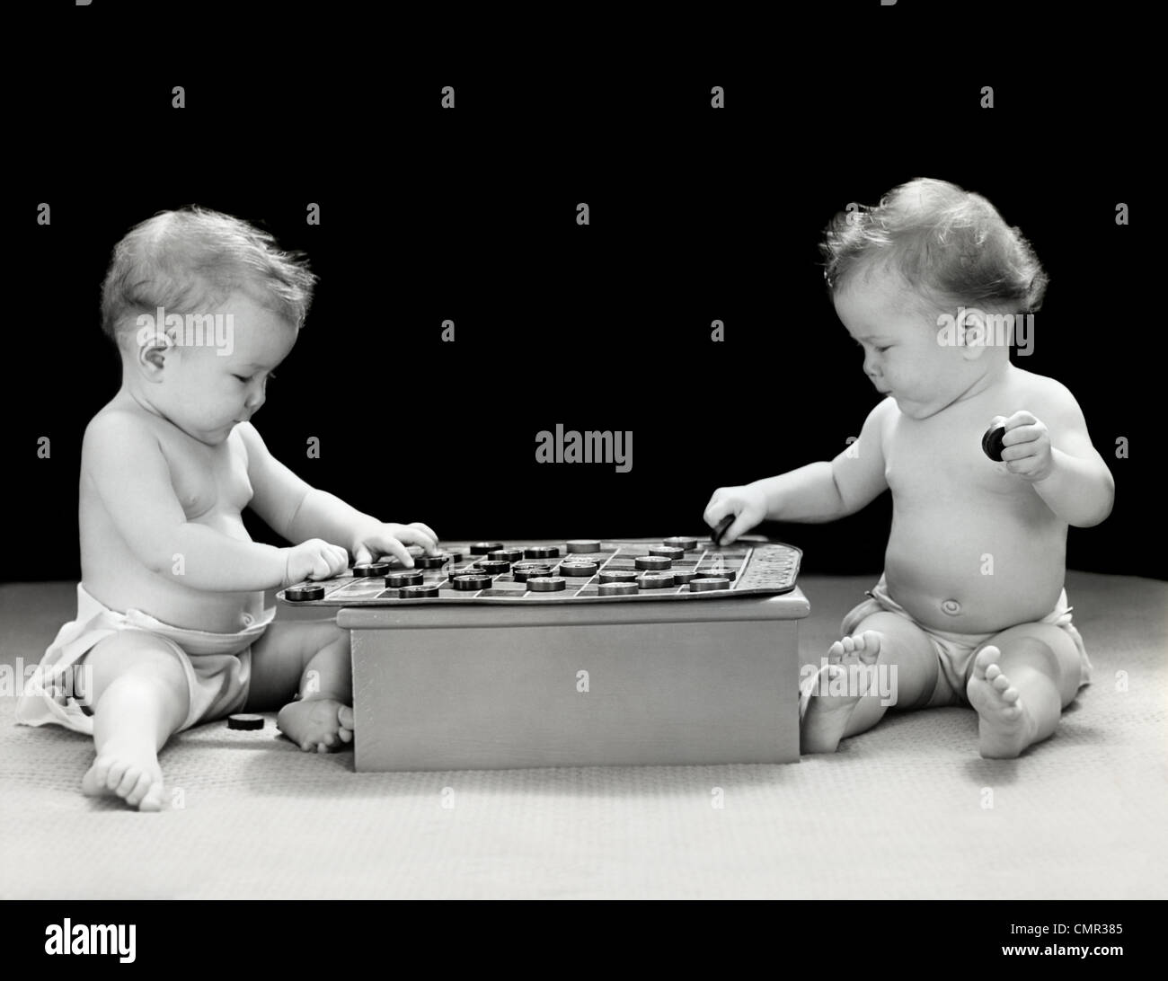 1930 1940 TWIN bebés jugando juego de damas juntos STUDIO Foto de stock