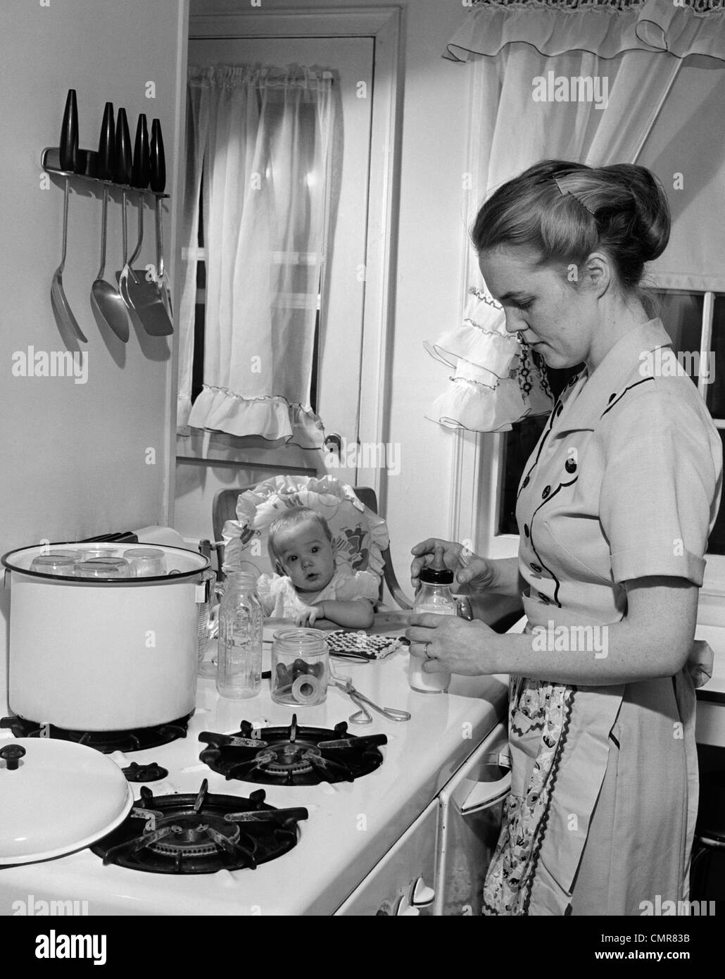 1950 En Una Trona De Bebé Ve La Madre En La Cocina En La Cocina Preparando La Botella De Leche 