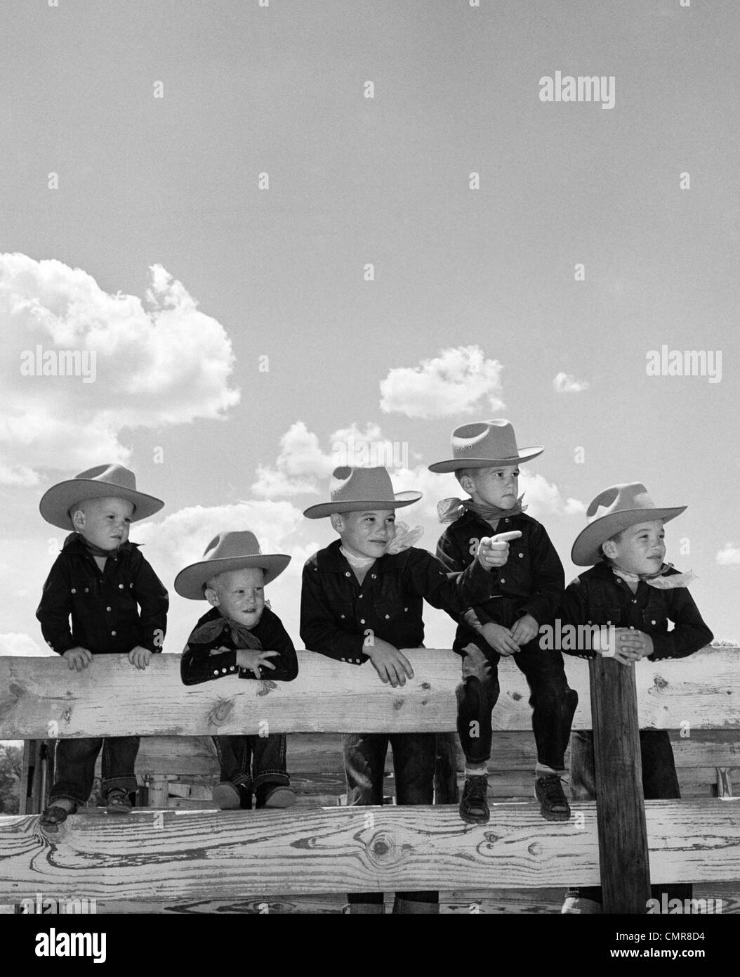 1950 Cinco VARONES hermanos vestidos como vaqueros sentados juntos en  corral valla Fotografía de stock - Alamy