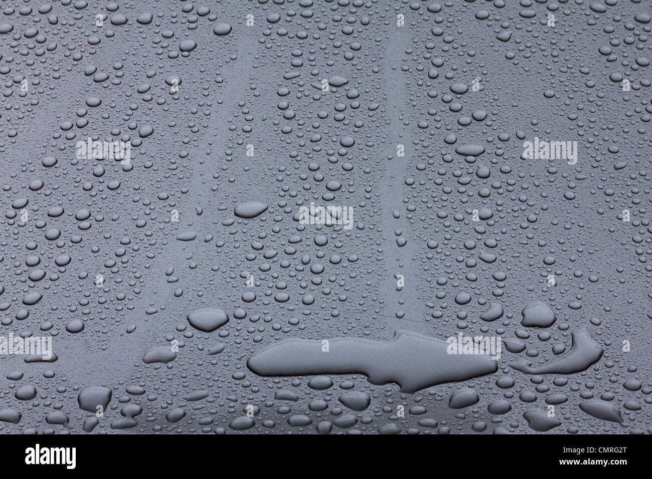 Las gotas de lluvia en un vehículo gris encerado capot Foto de stock