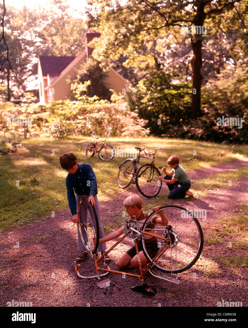 1970 1970 3 chicos cochera patio trasero de la casa suburbana DE TRABAJO DE  MANTENIMIENTO, REPARACIÓN DE BICICLETAS Las bicicletas retro Fotografía de  stock - Alamy