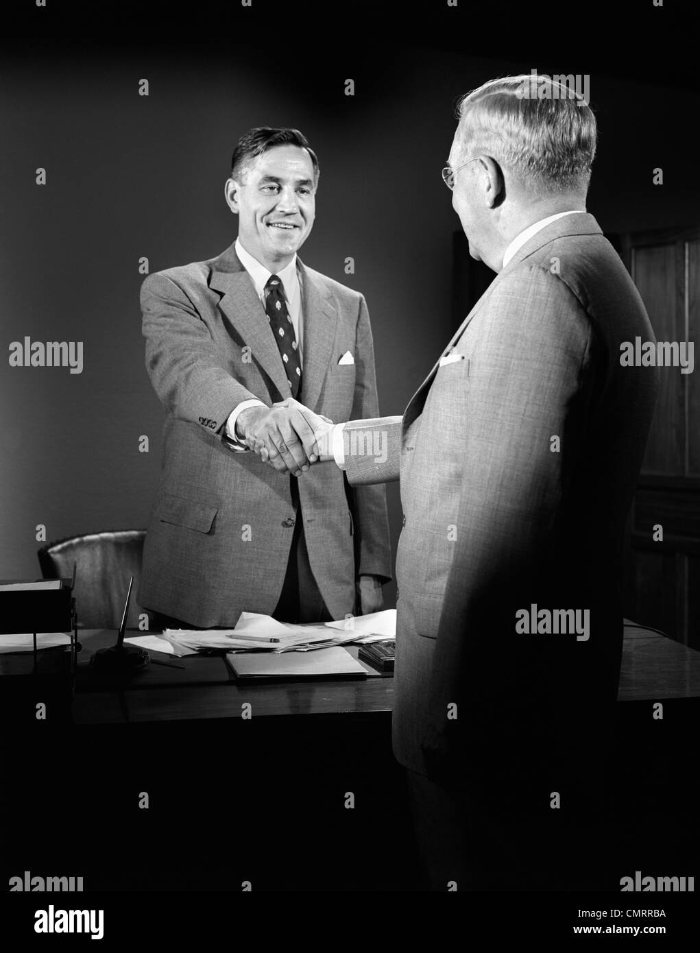 1950 trajes de estrechar las manos de los hombres de negocios de escritorio  de trabajo en papel Fotografía de stock - Alamy
