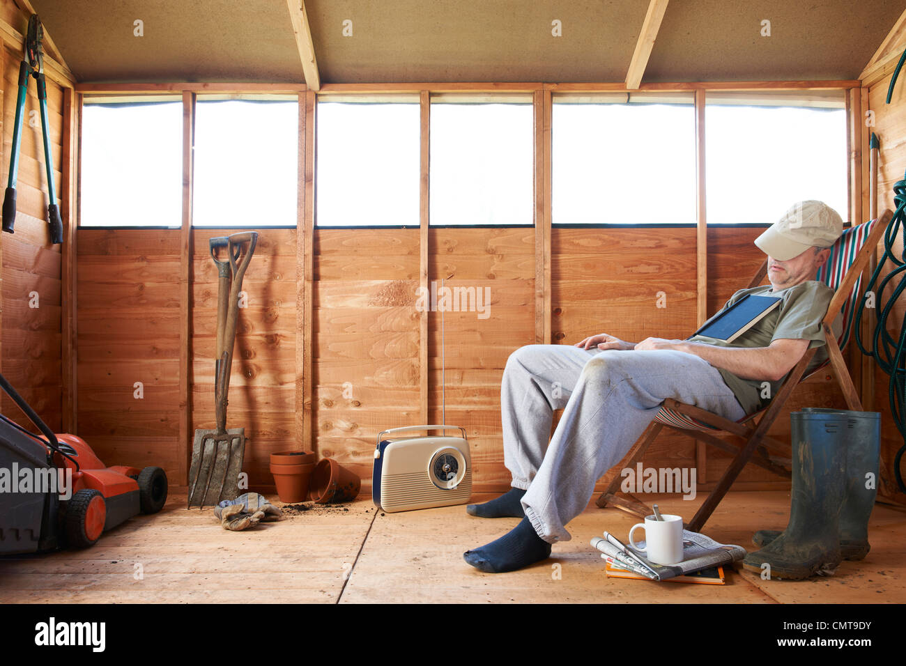 Hombre sentado en la hamaca para dormirse en el cobertizo Foto de stock