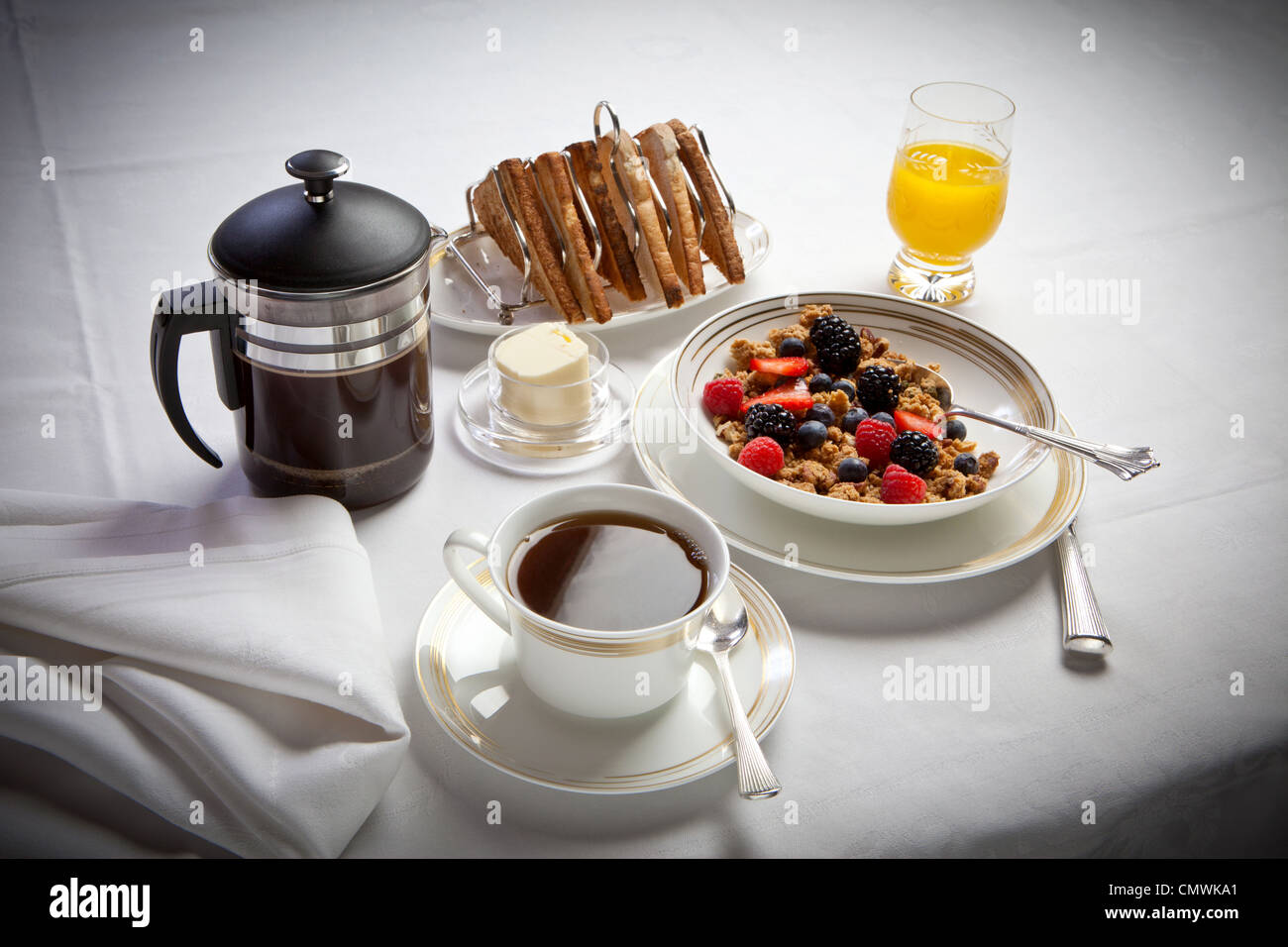 Desayuno continental con café y tostadas, cereales jugo establecidas sobre un mantel de lino blanco Foto de stock