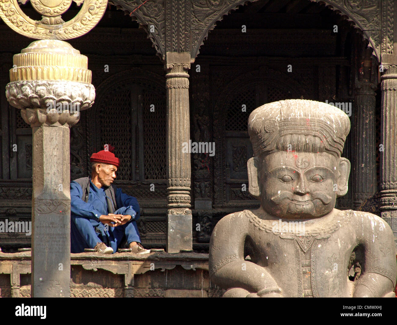 Un hombre nepalí se asienta en la reflexión profunda fuera de un templo en Bhaktapur. Foto de stock