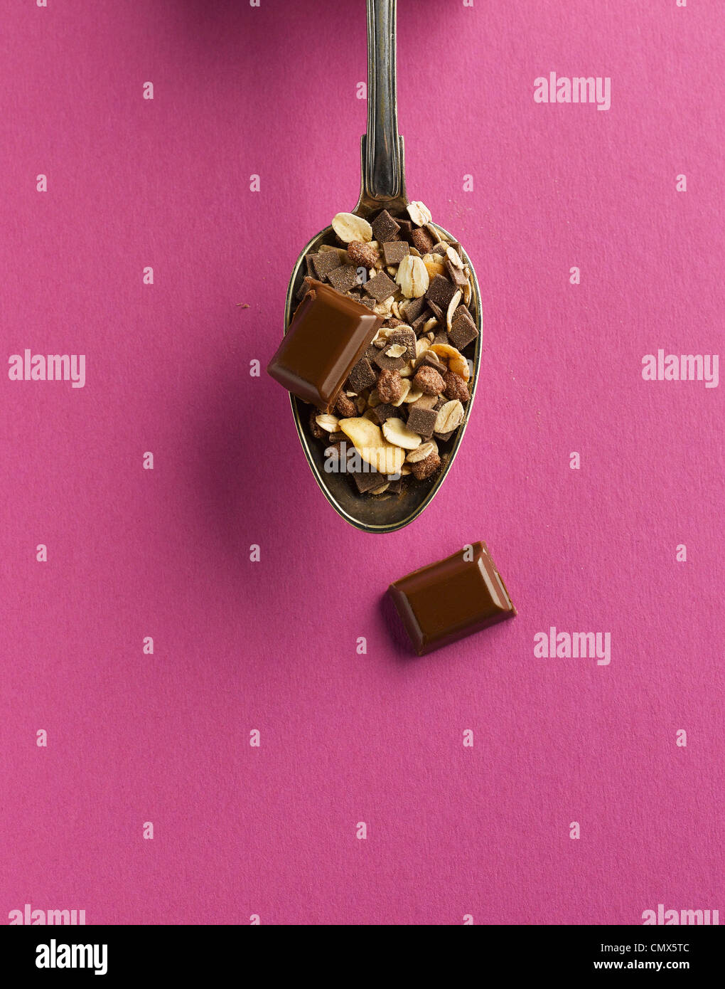Los cereales y el chocolate en una cuchara sobre fondo de color rosa Foto de stock