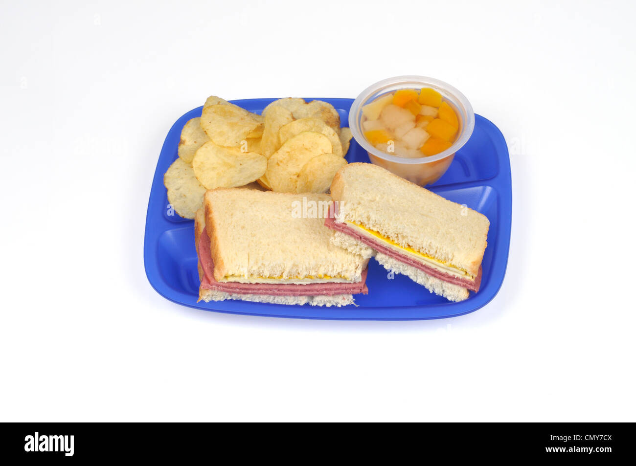 Bandeja de almuerzo escolar concepto con salami y queso sandwich, chips y copa de frutas Foto de stock