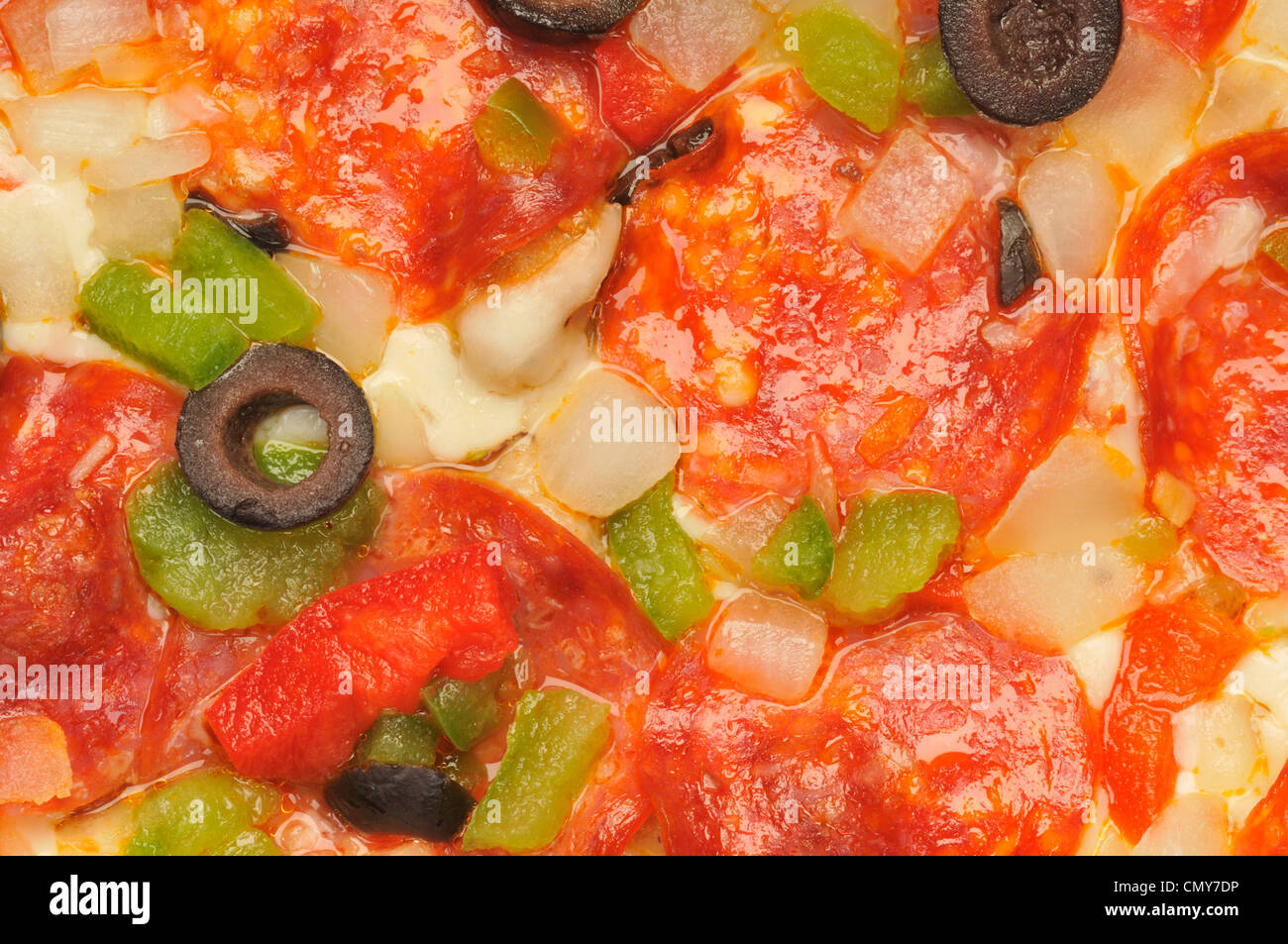 Macro de cerca el detalle de pizza con queso, pepperoni, pimientos rojos y verdes, cebollas y aceitunas negras Foto de stock