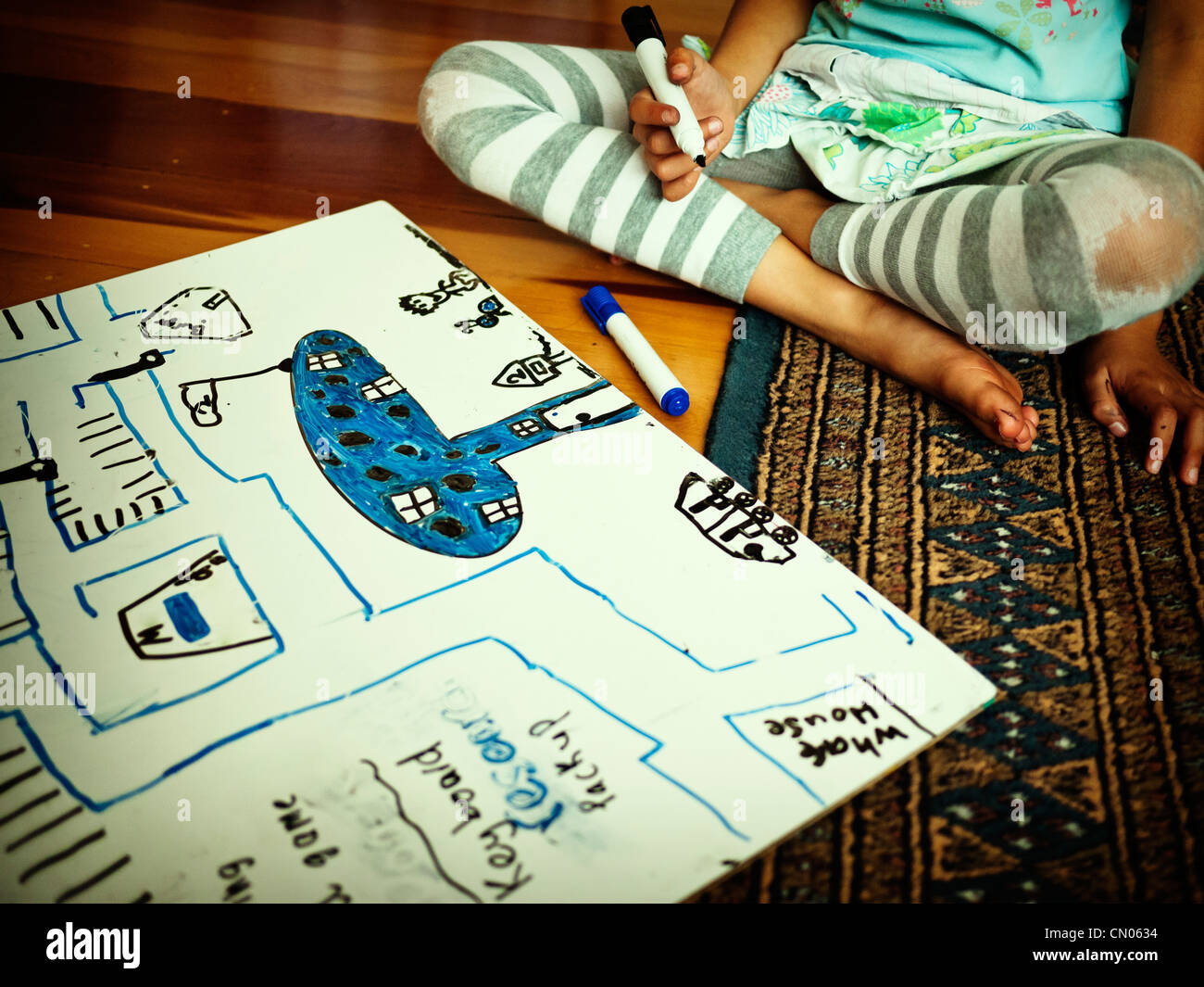 Chica dibuja el mapa con imágenes en la pizarra en el piso Foto de stock
