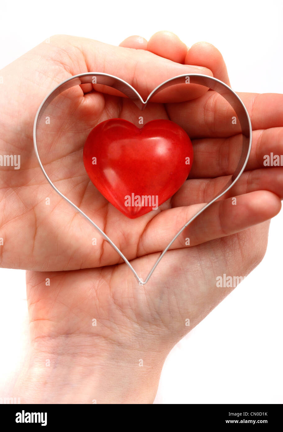 Imagen simbólica, enfermedad cardíaca, ataque al corazón, la protección, la prevención, la cardiología. Manos sosteniendo un corazón rojo. Foto de stock