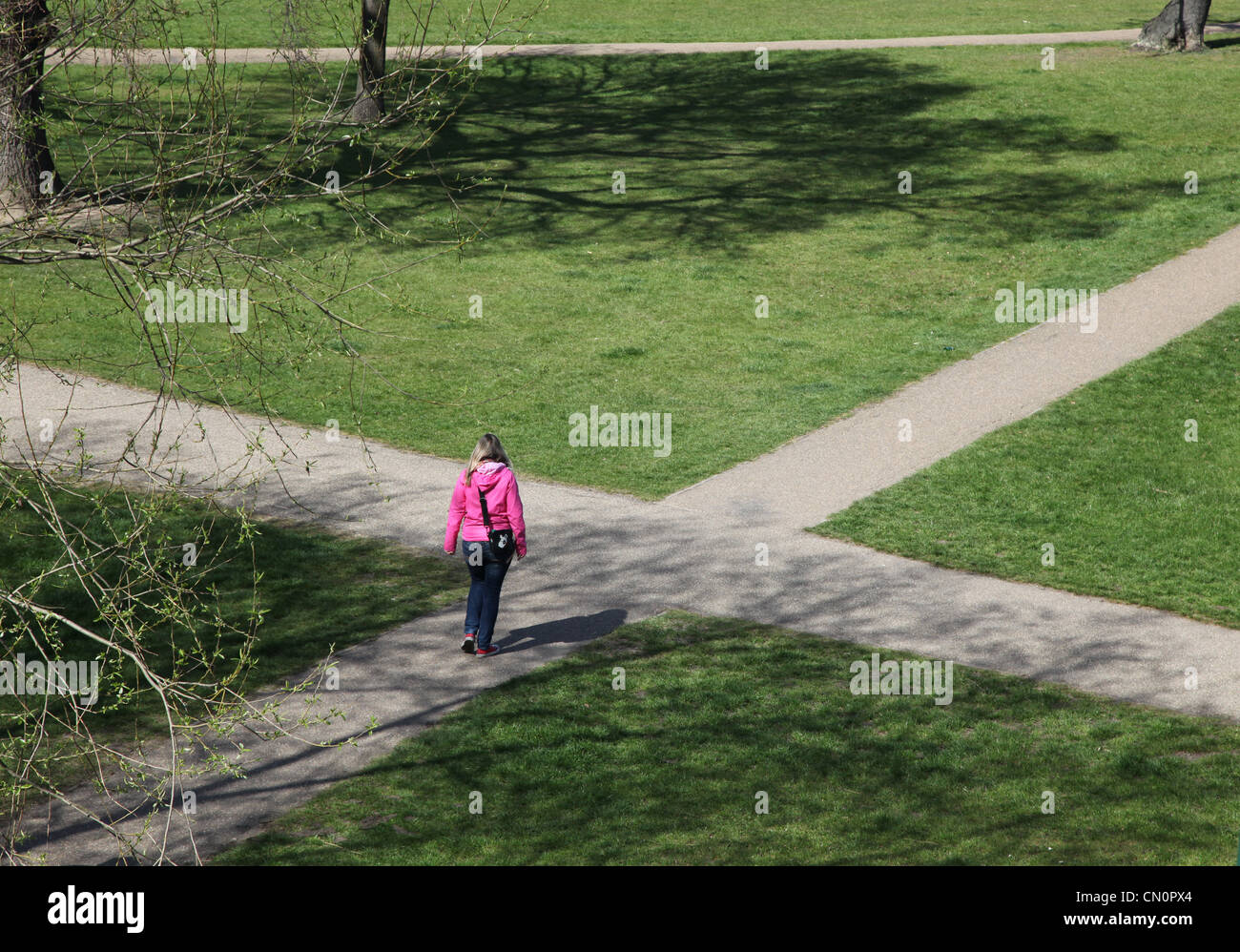 Una mujer en una encrucijada ruta, tomar una decisión sobre qué camino tomar. Foto de stock