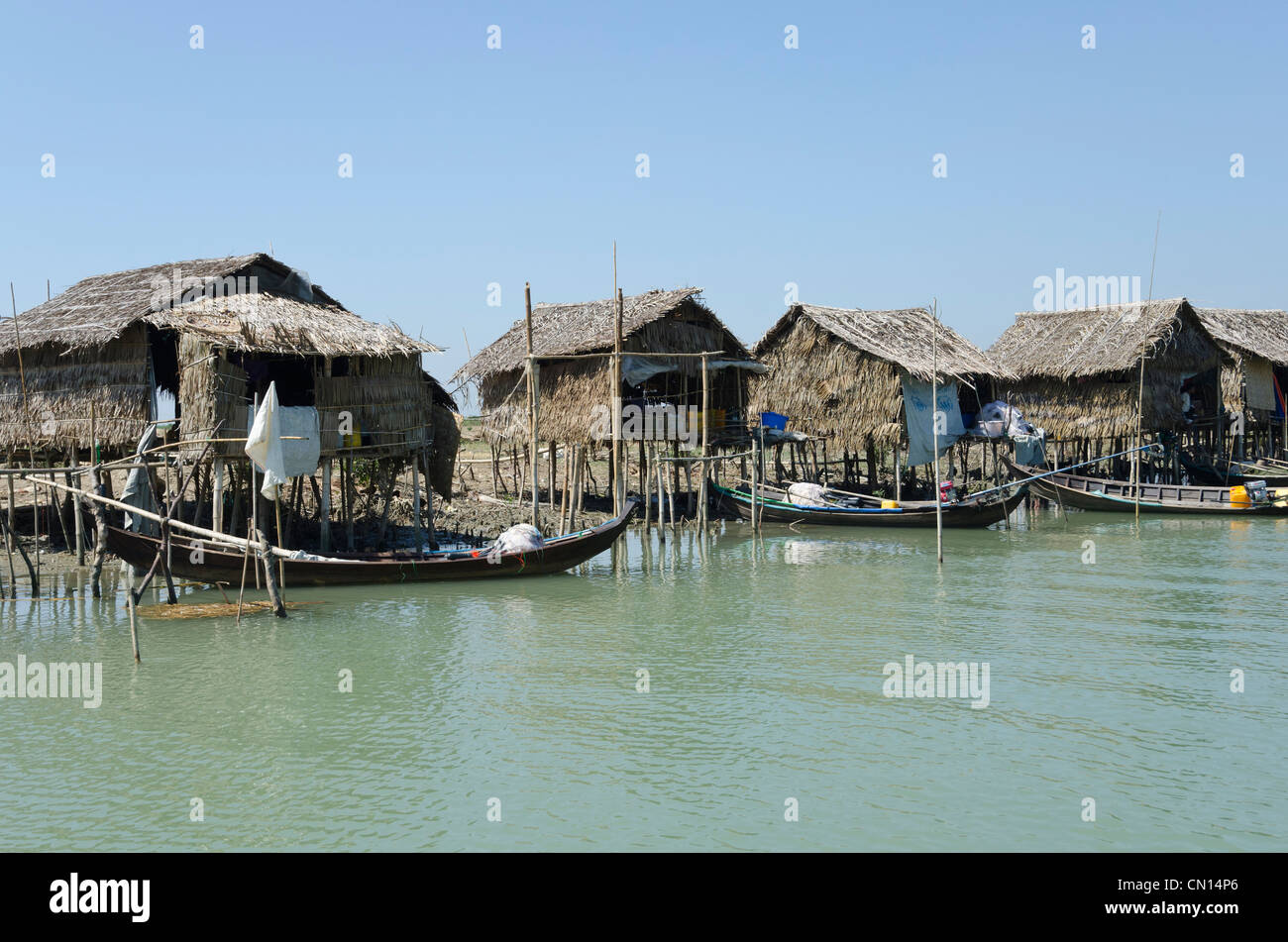 Cabañas de bambú y botes a lo largo de una vía navegable. Delta del Irrawaddy. Myanmar. Foto de stock