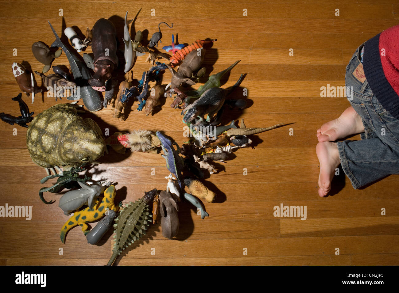 Niño chico con animales de juguete en el piso Foto de stock