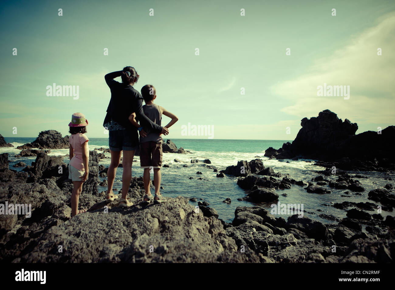 Madre, hijo, hija, mira sobre el océano austral, Cape Palliser, Nueva Zelanda. Foto de stock