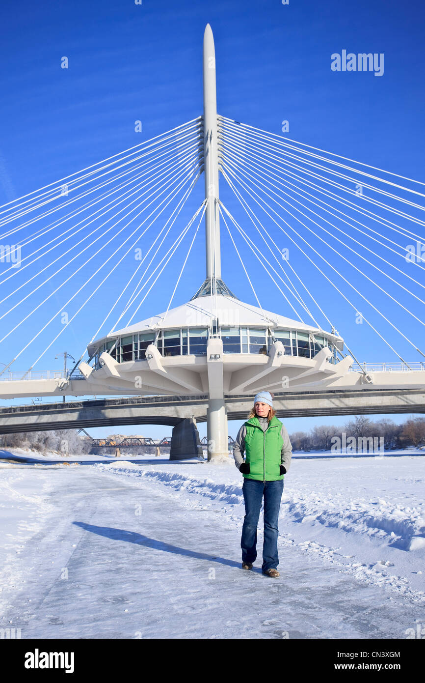 Mujer paseando el congelado Río rojo delante de la Explanada Arador Bridge, las horquillas, Winnipeg, Manitoba Foto de stock