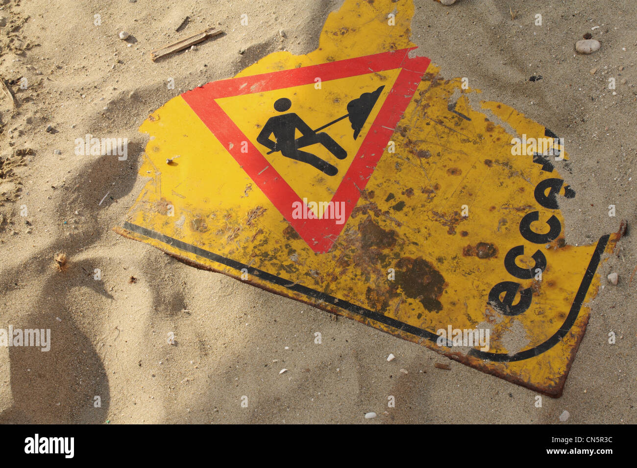 Un 'wok in progress' señales de carretera parcialmente enterrado bajo una capa de arena. Signo de la alta contaminación de la playa. Foto de stock