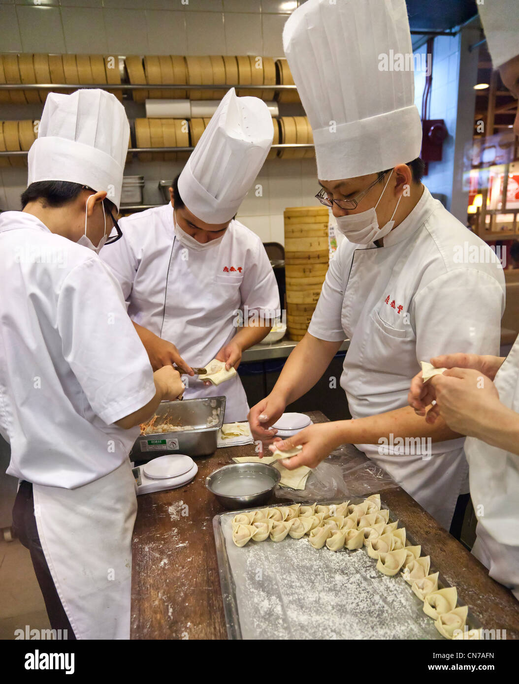 Chino chefs preparando dumplings en una cocina, bambú steamers Foto de stock