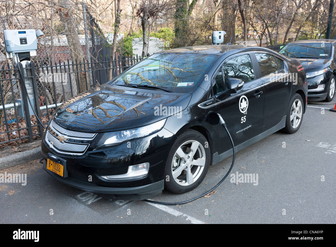 Un coche eléctrico híbrido Chevy Volt, utilizado por el Departamento de Parques de la ciudad de Nueva York, recibe un cargo en una estación de carga, en Central Park. Foto de stock