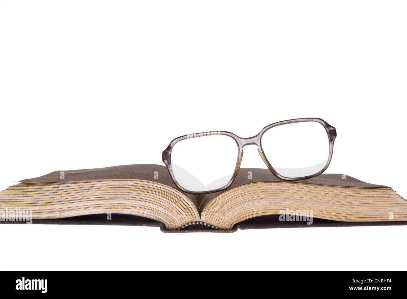 Viejas gafas en las monturas de plástico descansando descentrada en viejo,  amarillento libro abierto. Frontal vista horizontal. Aislado en blanco  Fotografía de stock - Alamy