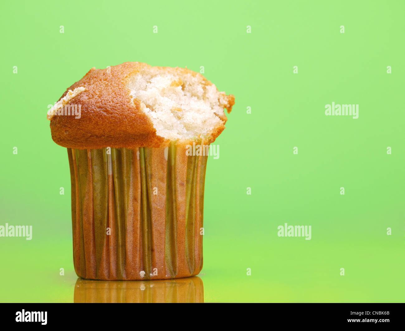 Delicioso cupcake con mordida tomado shot sobre fondo verde claro Foto de stock