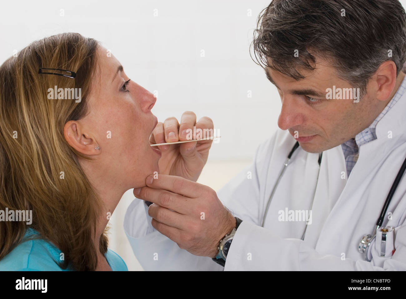 ENT médico examinar la faringe de un ambulatorio femenino Foto de stock
