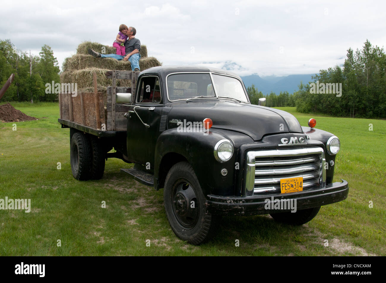 Abuelo besa a su nieta mientras se sientan en los fardos de heno apiladas en la parte trasera de un camión, clásico en Palmer, Alaska Foto de stock