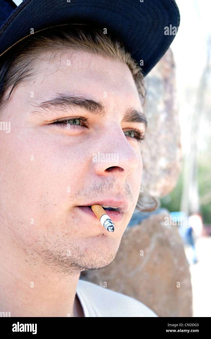 Cerca de un hombre joven de veintitantos años, fumar un cigarrillo. Foto de stock