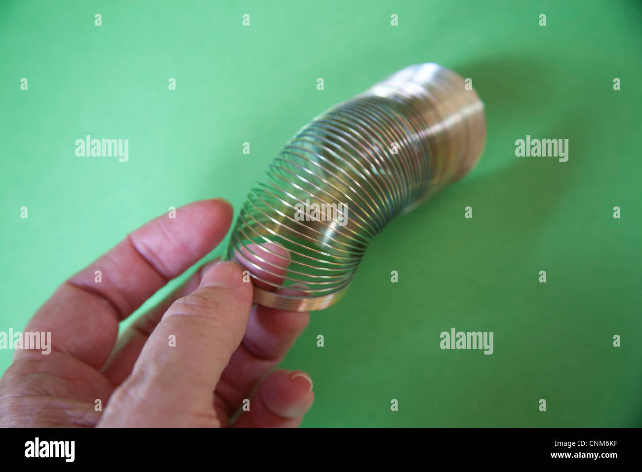 Moviendo la mano Slinky o perezoso juguete de resorte hechas de un resorte helicoidal que se extiende y puede rebotar hacia arriba y hacia abajo Foto de stock