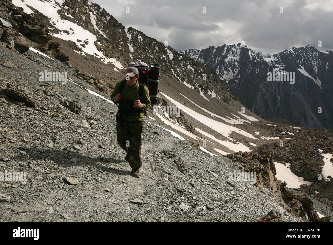 Trekker sube a la montaña Telety Pass (3,759 m) en la cordillera Terskey Ala-Too de Tian Shan, en Kirguistán. Foto de stock