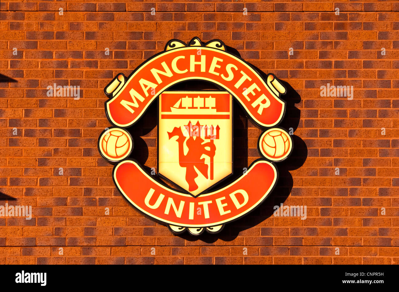 Emblema del Manchester United en la pared fuera de las Naciones store, Old Trafford, Manchester, Inglaterra, Reino Unido. Foto de stock