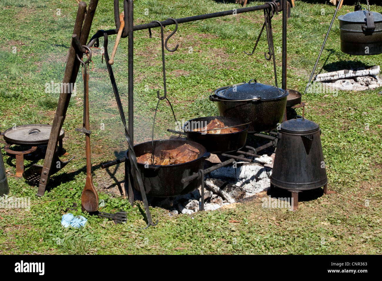 Cocinar en un fuego de campamento, con ollas de hierro fundido y cafetera,  afuera en el sol Fotografía de stock - Alamy