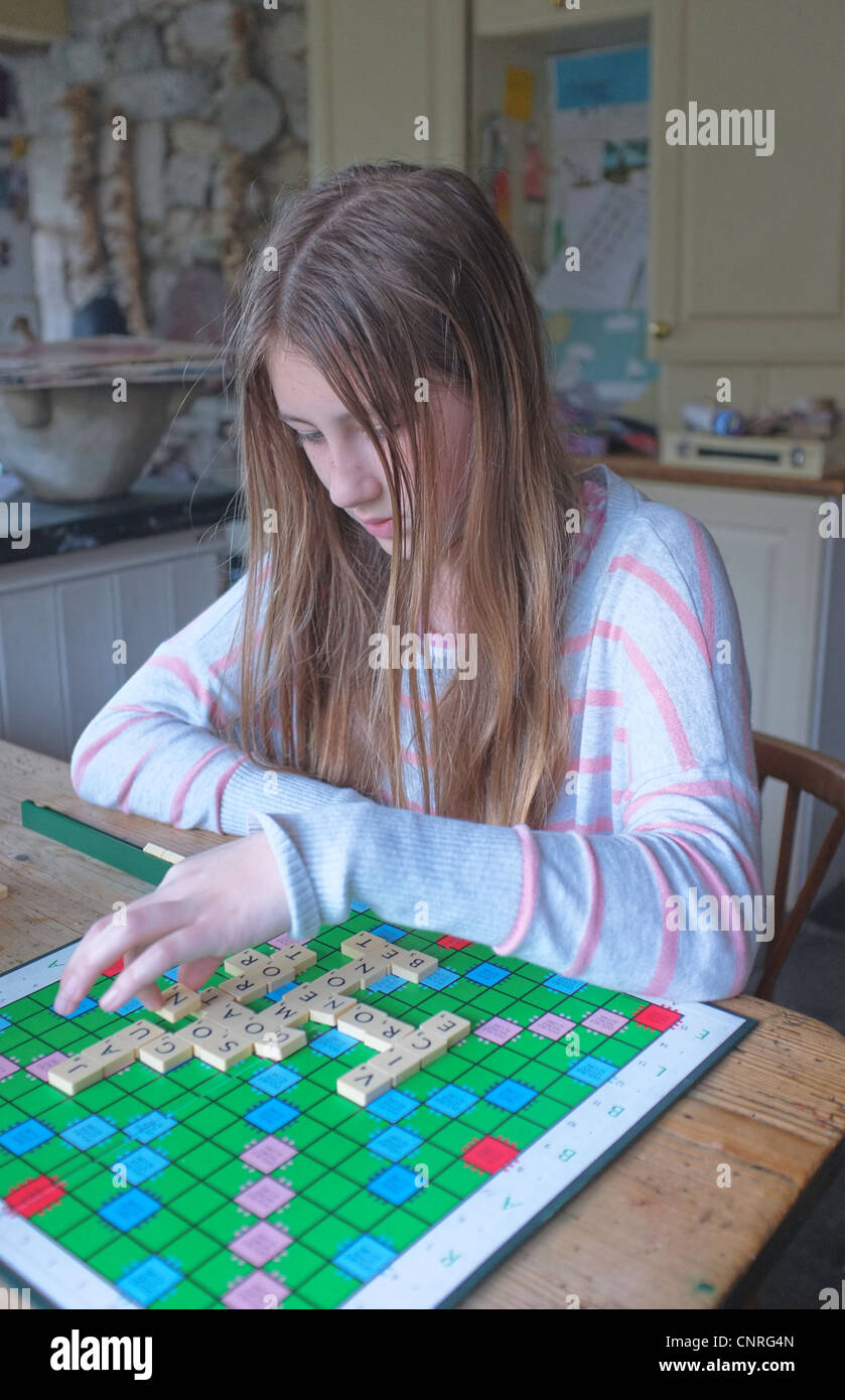 Una niña de 11 años de edad jugando Scrabble en una cocina Foto de stock