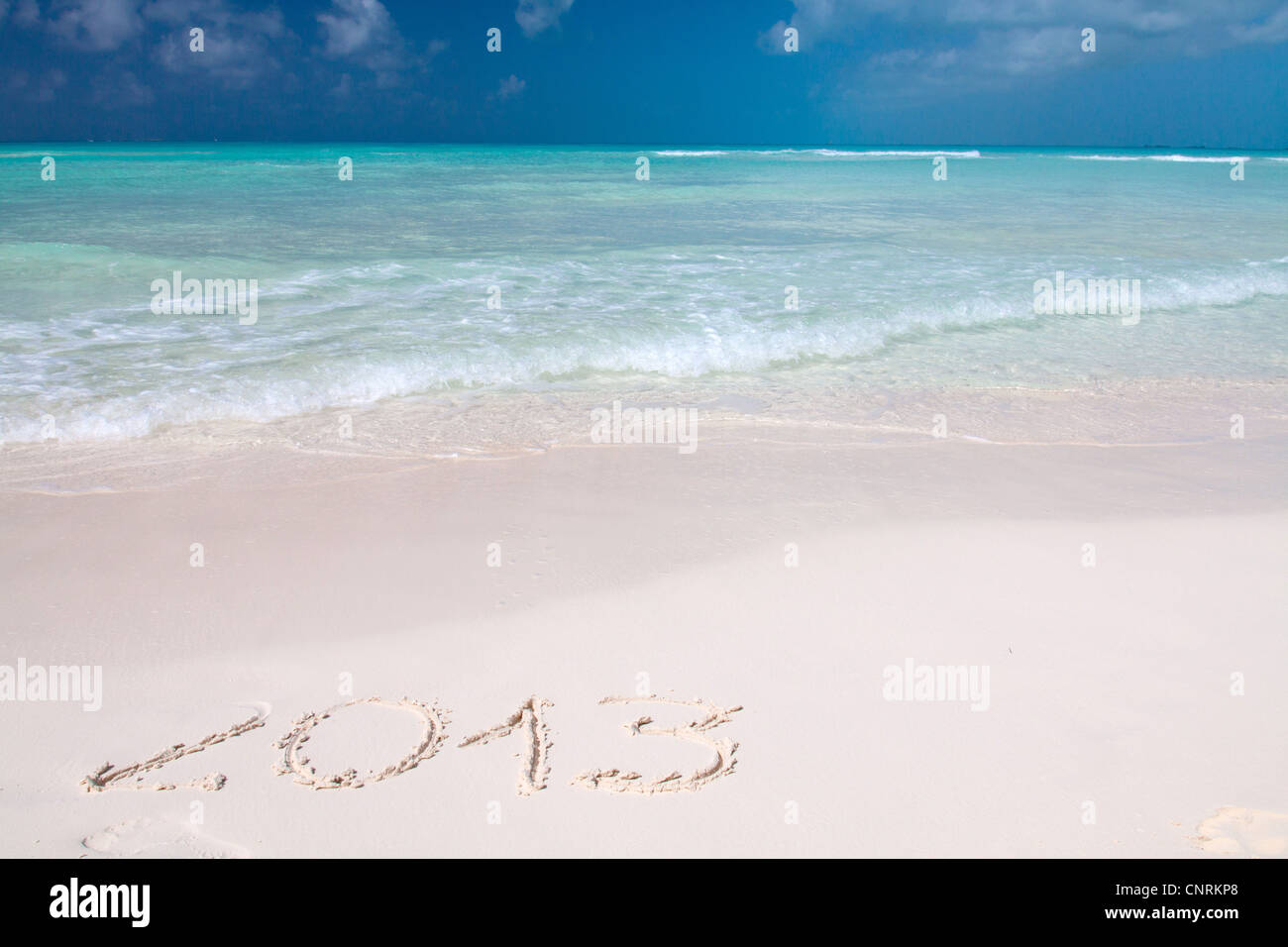 Año 2013 escritos a mano en la arena blanca frente al mar Foto de stock