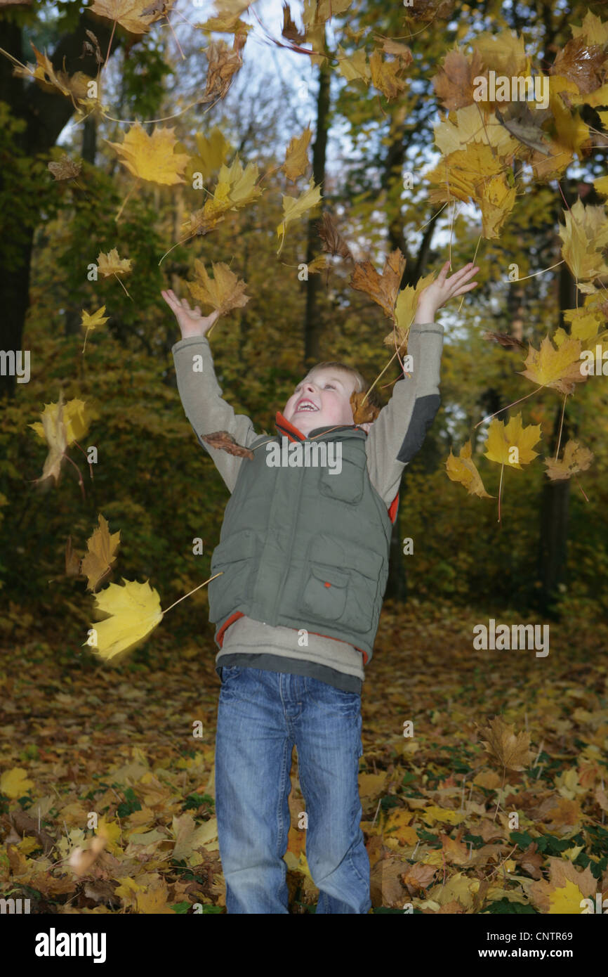 Niño jugando en hojas de otoño Foto de stock