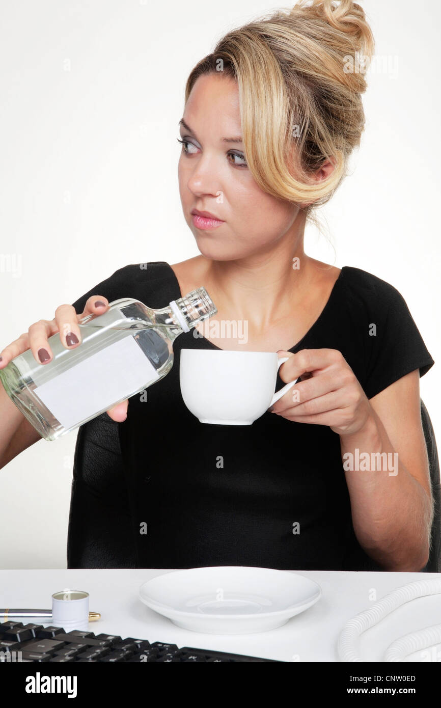 Una mujer con un alcohol en el trabajo verterlo en su copa para que nadie sabrá Foto de stock