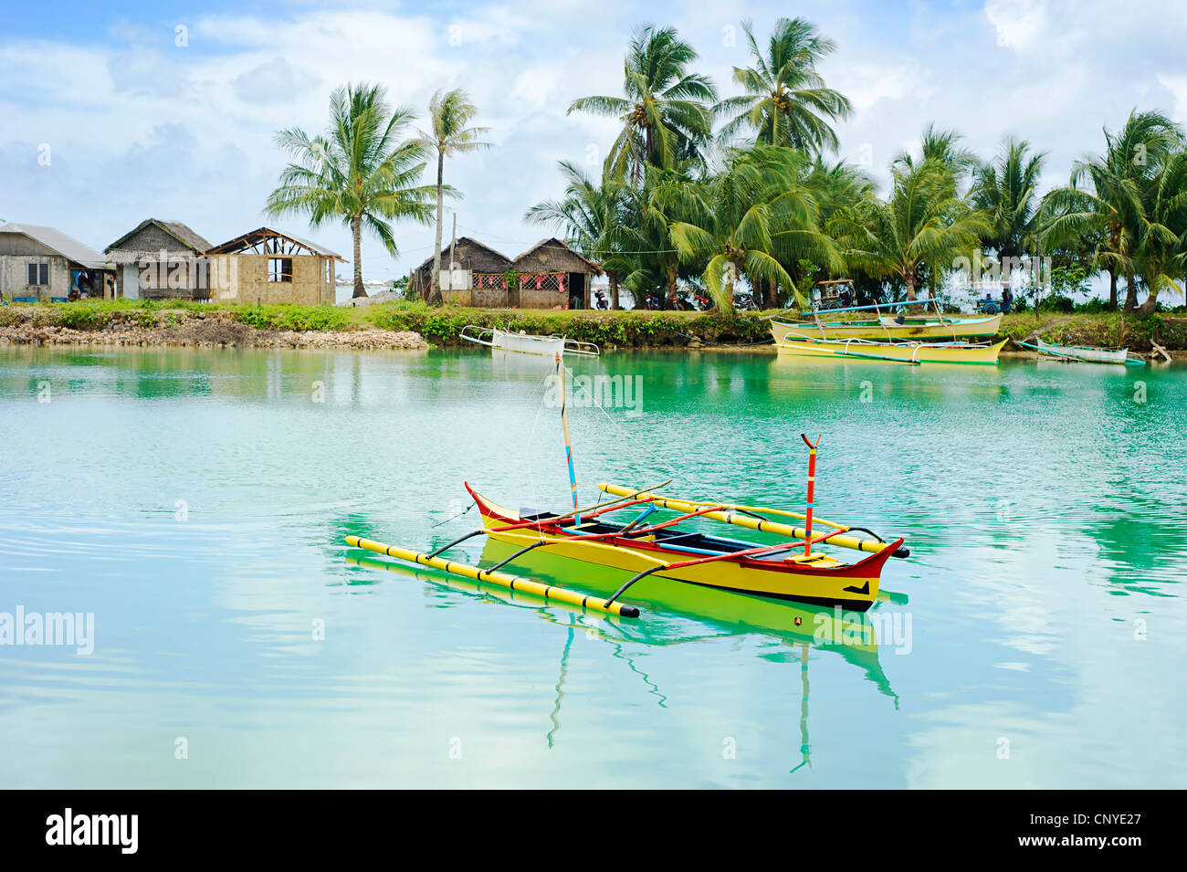 El paisaje tropical con los tradicionales barcos de Filipinas y aldea en Calicoan isla, Filipinas Foto de stock