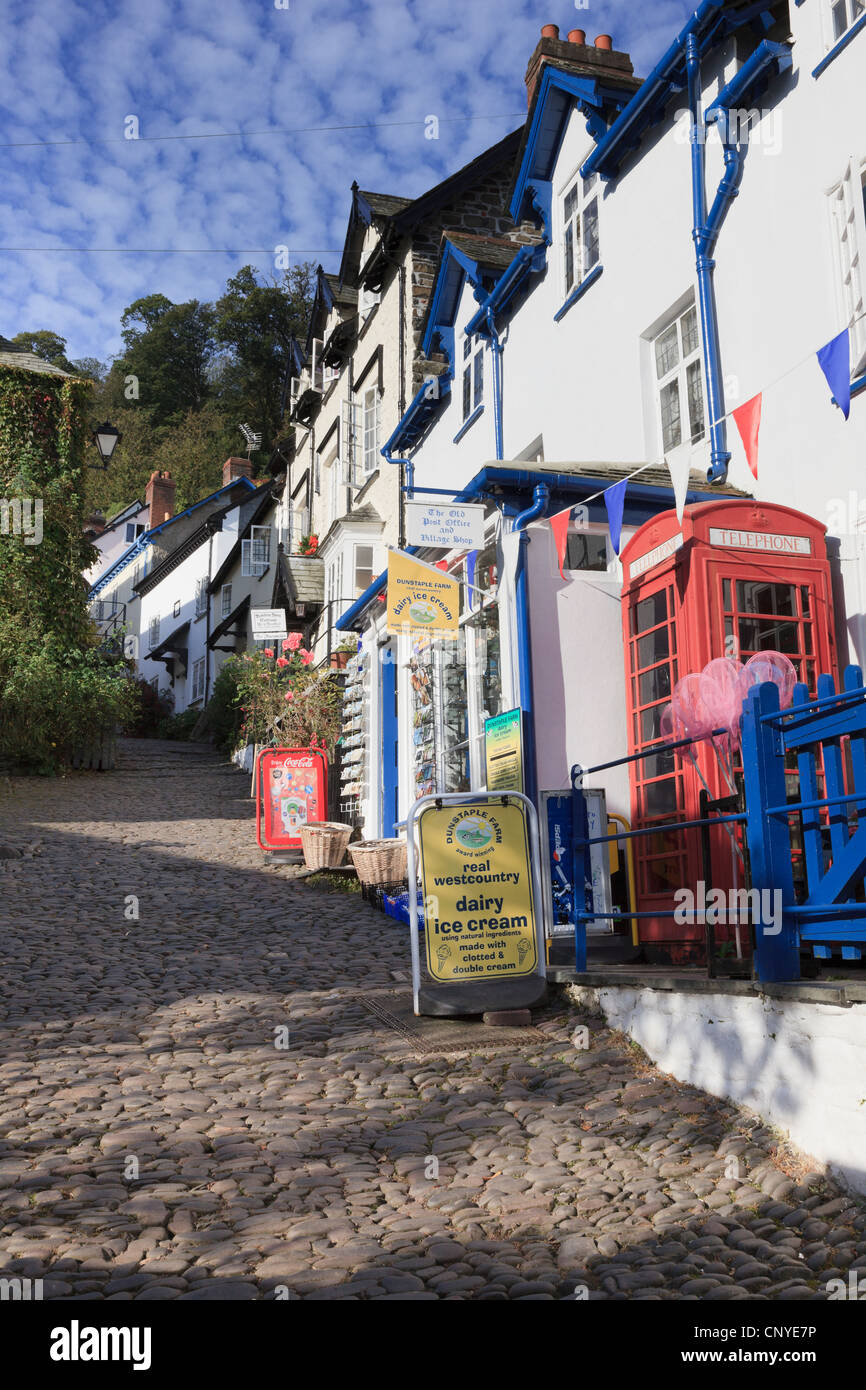 Vista de empinadas y estrechas calles empedradas en el pintoresco pueblo con tienda y teléfono rojo cuadro en Clovelly Devon, Inglaterra Gran Bretaña Foto de stock
