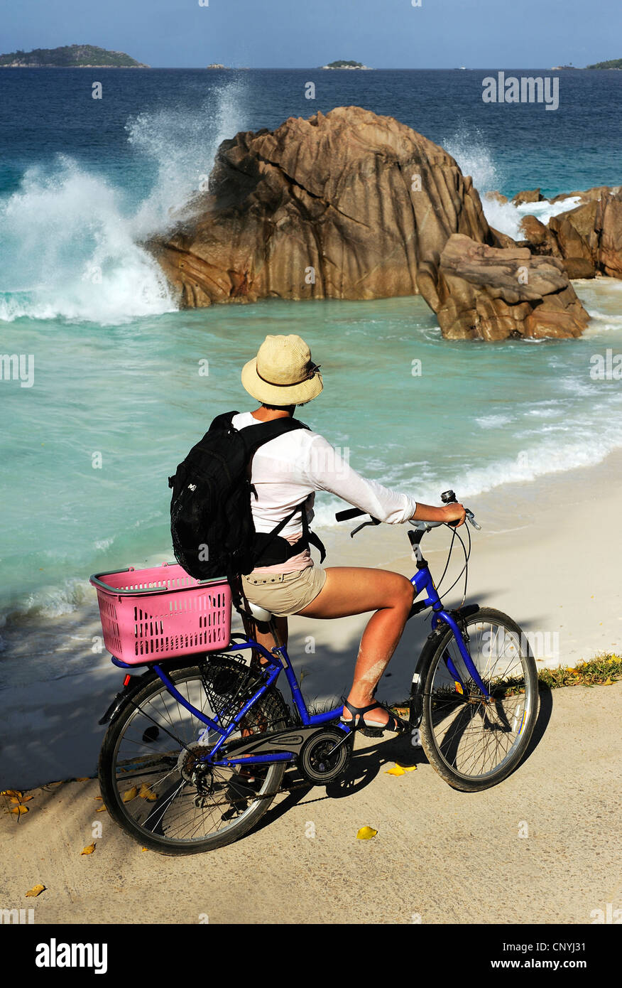 Ciclista en la playa de Anse Patatran observando el romper de las olas, Seychelles, La Digue Foto de stock
