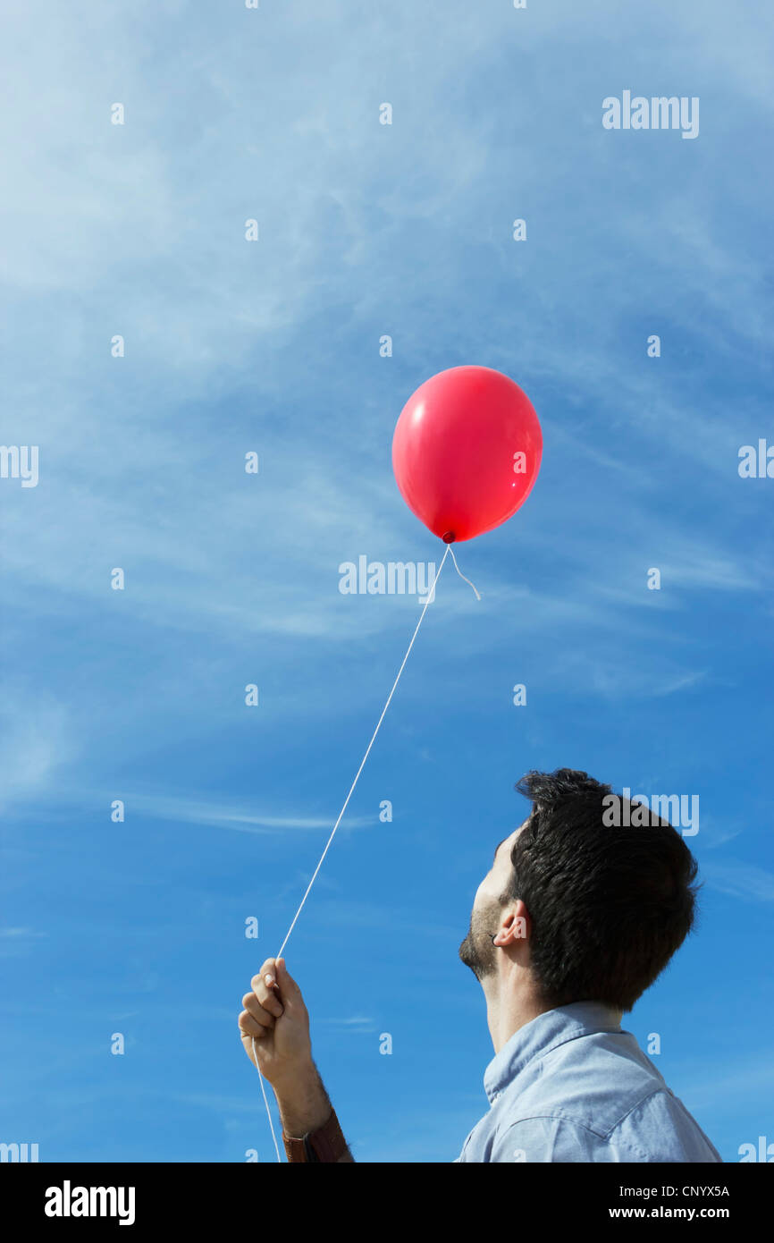 Vista posterior del joven volando en un globo rojo Foto de stock