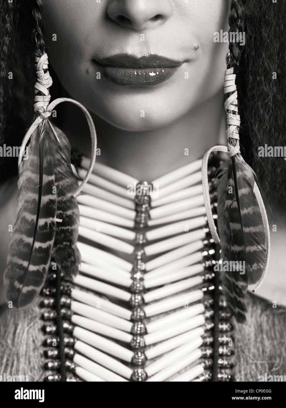 Artístico closeup retrato de una mujer vistiendo los aborígenes nativos collar accesorios y plumas en su pelo. Cerca de labios Foto de stock