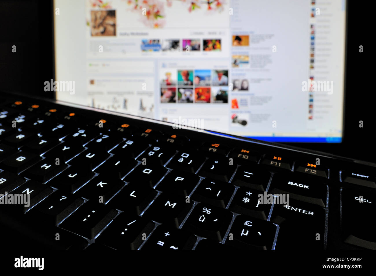 Calculador negro teclado retroiluminado iluminada con caracteres blancos sobre las teclas y la pantalla del PC en la oscuridad Foto de stock