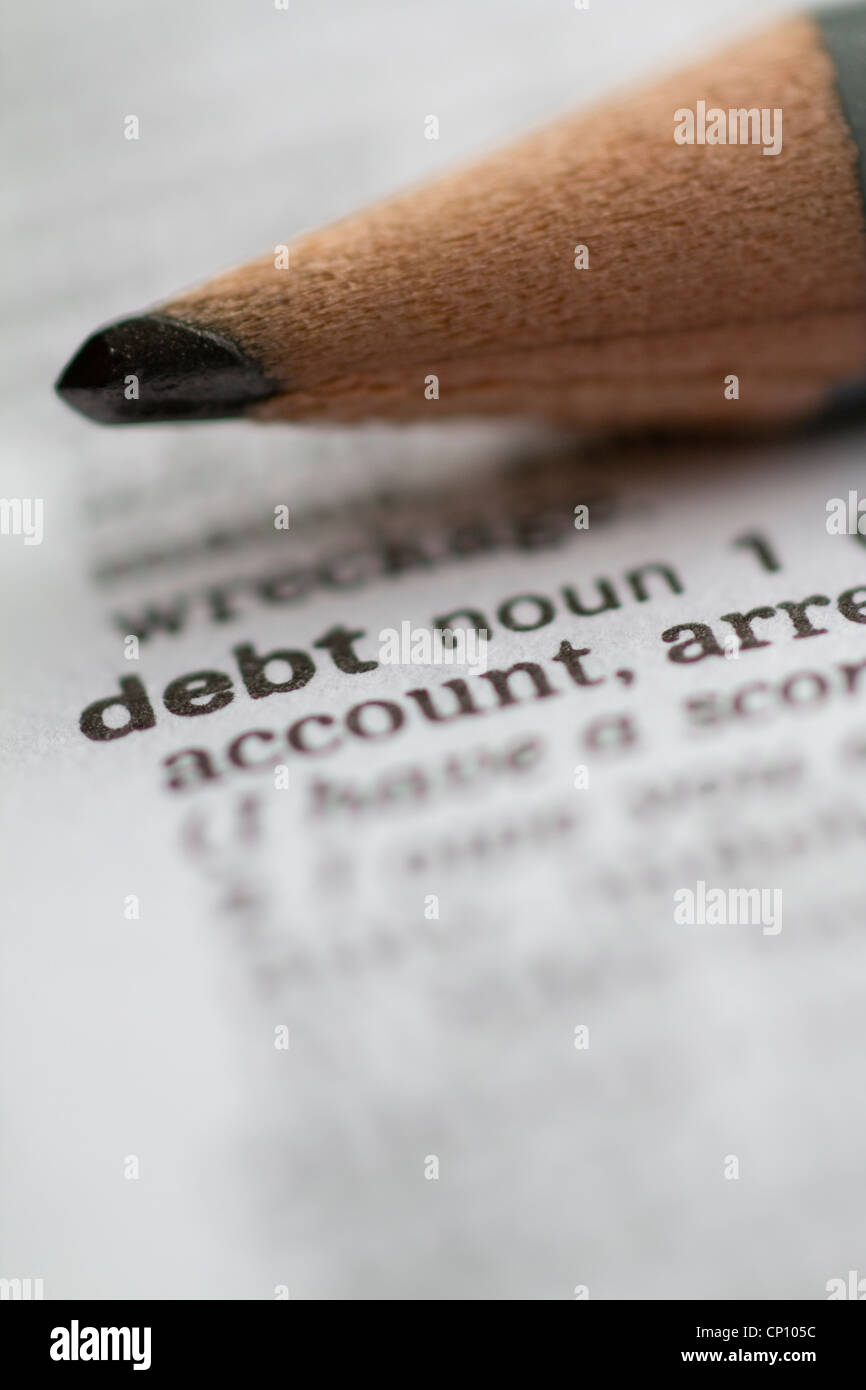 La palabra deuda deuda con lápiz en el diccionario. Foto de stock