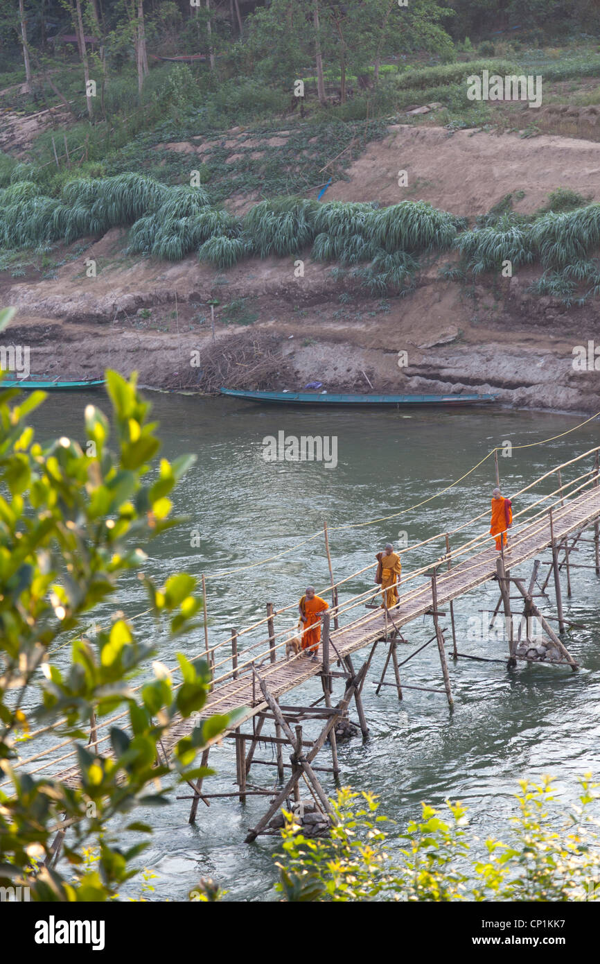 Los monjes novicios utilizando el puente de bambú endebles lanzados por el Khan, un afluente del río Mekong, Luang Prabang (Laos). Foto de stock