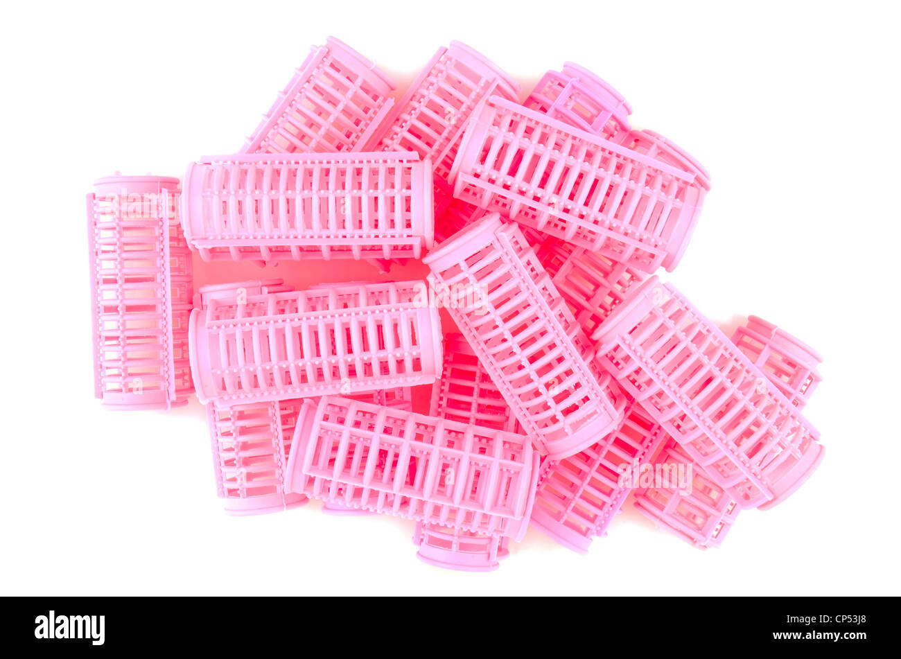 Rizadores de pelo rosa de plástico en un patrón aleatorio sobre un fondo blanco con leves sombras. Foto de stock