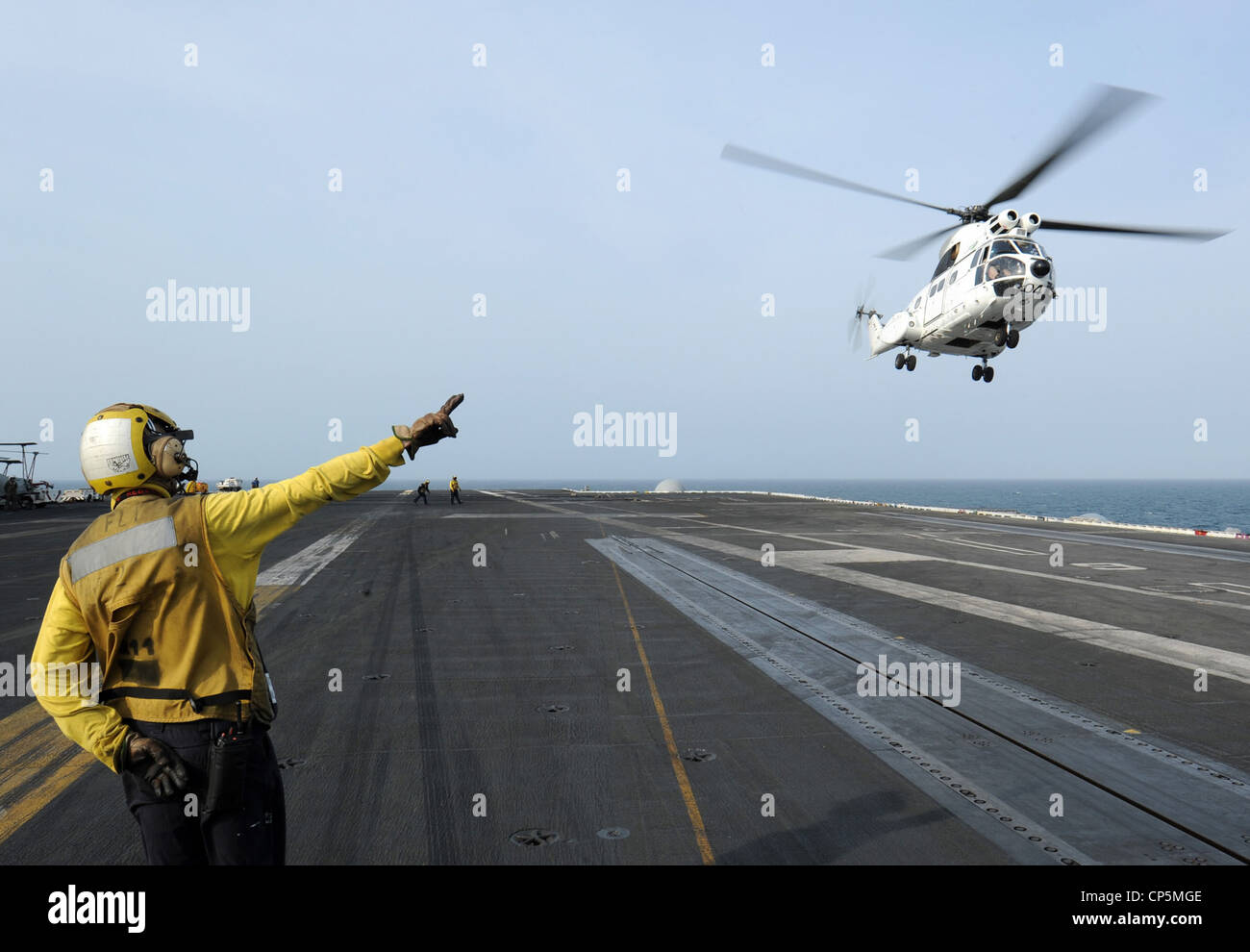 Aviación BoatswainÕs Mate (Manejo) 2da clase Steven P. Lilly envía señales  a un helicóptero SA-330J Puma mientras se levanta de la cubierta de vuelo  del portaaviones USS George H.W. Casquillo (CVN 77).