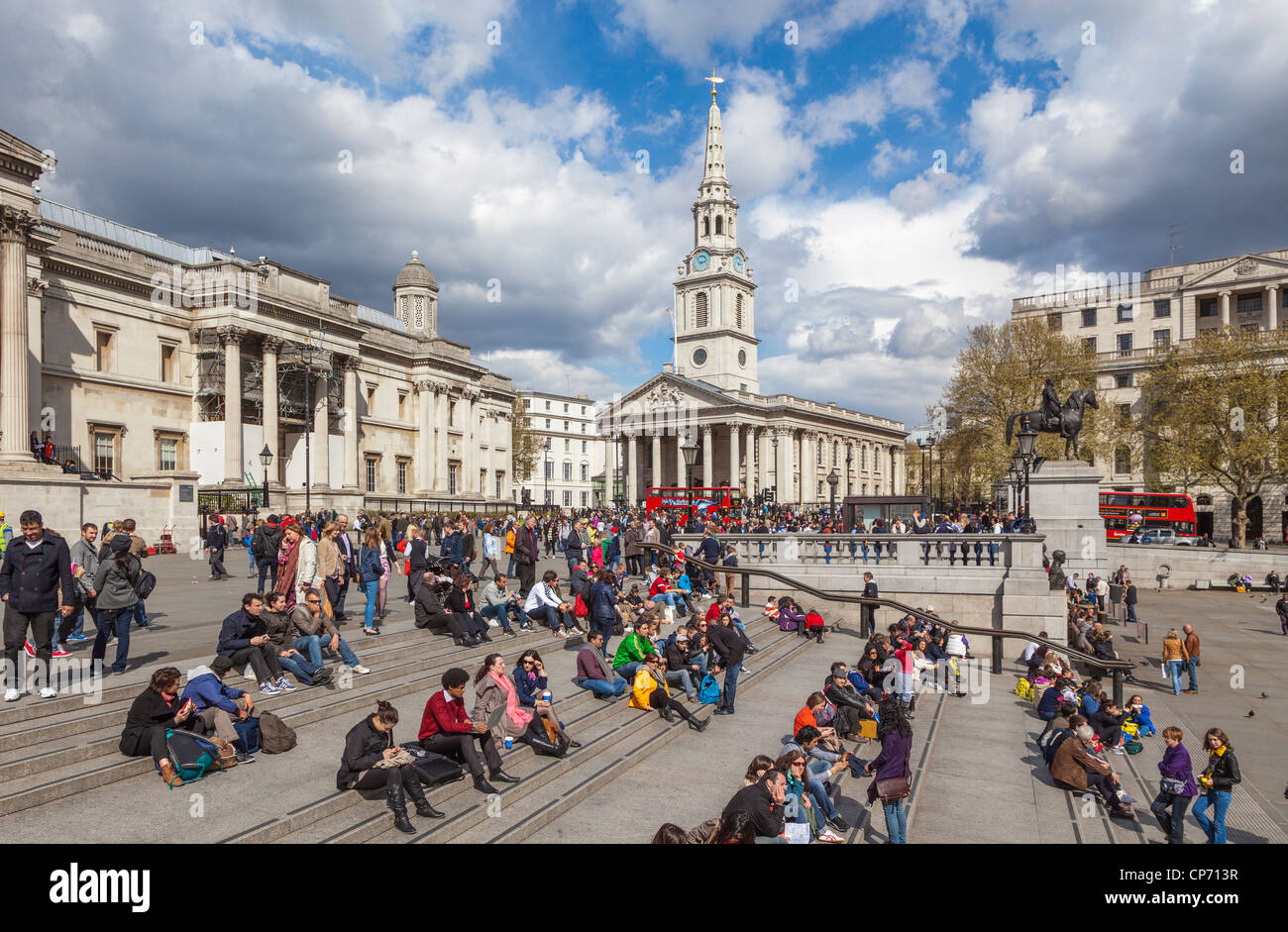 Trafalgar Square con turistas relajarse en pasos y St Martins-en-el-campos en el fondo. Foto de stock